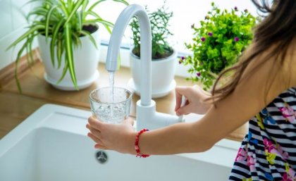 Child filling glass with water from kitchen tap